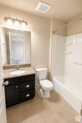 Full Bathroom featuring a dark wood-finish vanity, stone-composite countertop with an integrated basin, three-bulb vanity light fixture, and a white acrylic shower-tub surround