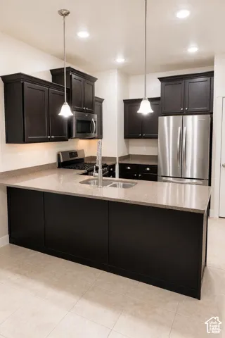 Kitchen featuring dark cabinetry, granite countertops, stainless steel appliances, recessed ceiling lighting, and pendant fixtures