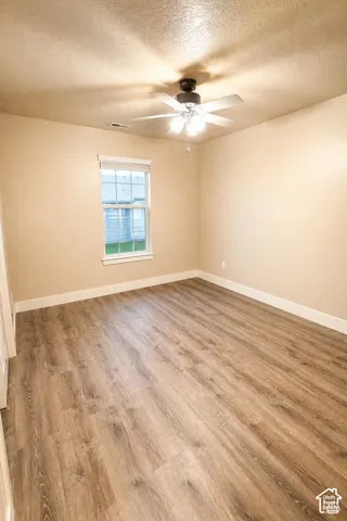 Bedroom featuring wood-finish flooring, a neutral paint palette, a single window, and a ceiling fan with integrated lighting