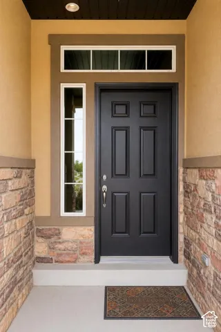 Multi-story exterior featuring stucco, stone accents, recessed balcony with metal railing, and attached multi-car garage