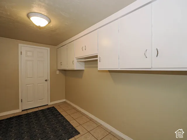 Wall-mounted white cabinetry featuring integrated hardware, tile flooring, and a flush-mount ceiling light fixture