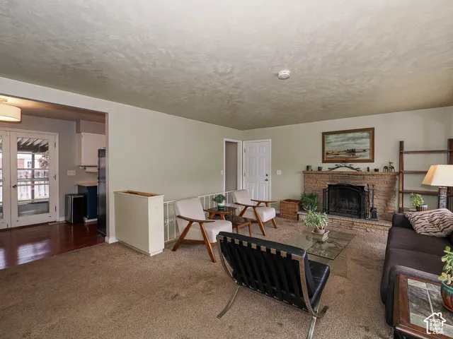 Living area featuring a masonry fireplace with a stone hearth, carpeted flooring, and a glass-paned door providing exterior access