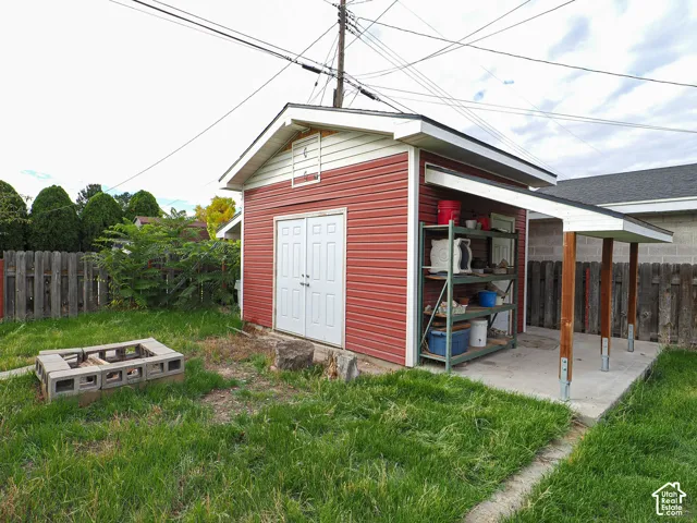 Detached storage structure with dual entry doors, siding exterior, and a concrete patio pad with an attached covered lean-to
