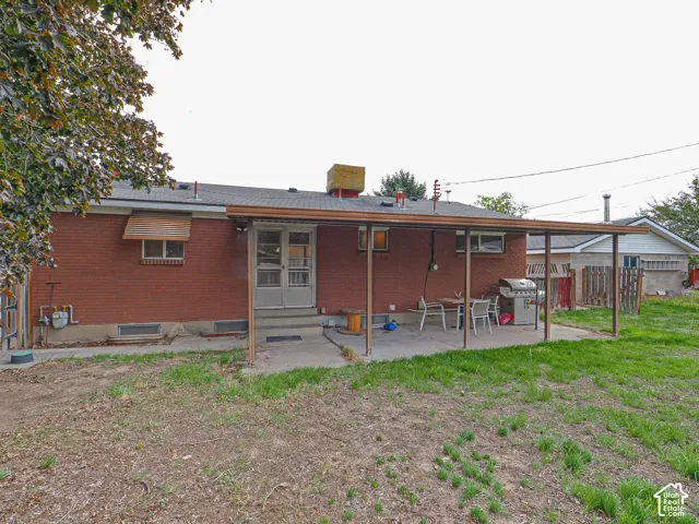 Brick exterior featuring a covered patio, concrete hardscaping, and metal window awnings