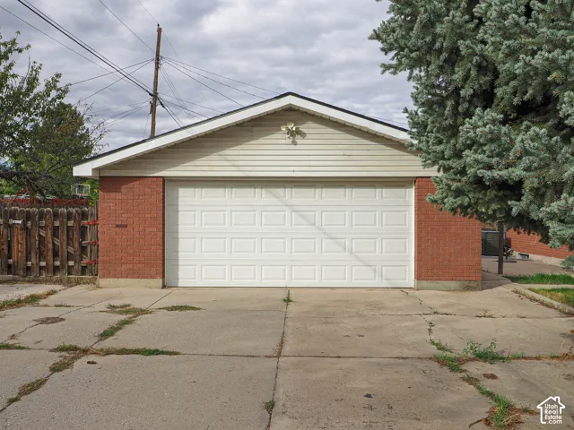 Detached garage featuring a brick and horizontal siding exterior, gable roofline, and a multi-panel overhead garage door