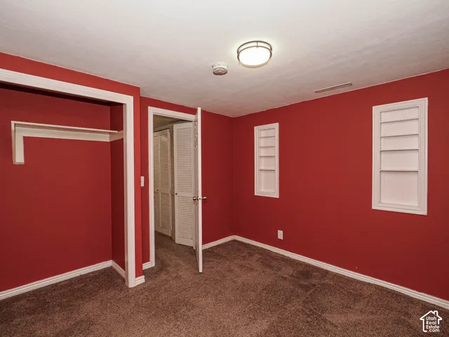 Interior room featuring wall-to-wall carpeting, two built-in wall niches with shelving, a reach-in closet with built-in shelving, and a louvered closet door