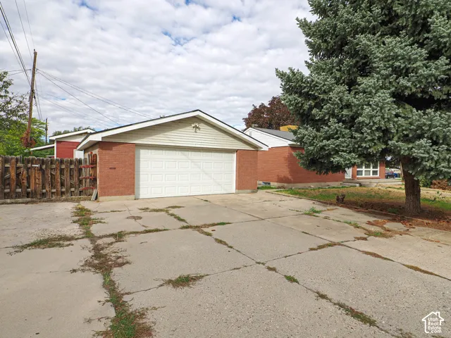 Detached two-car garage featuring brick and horizontal siding, a paneled sectional door, and an expansive concrete parking area