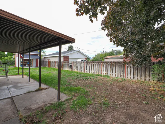 Covered concrete patio, fenced backyard, detached garage, and storage shed
