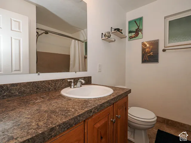 Vanity featuring a stone-patterned countertop, drop-in sink, and wood cabinetry
