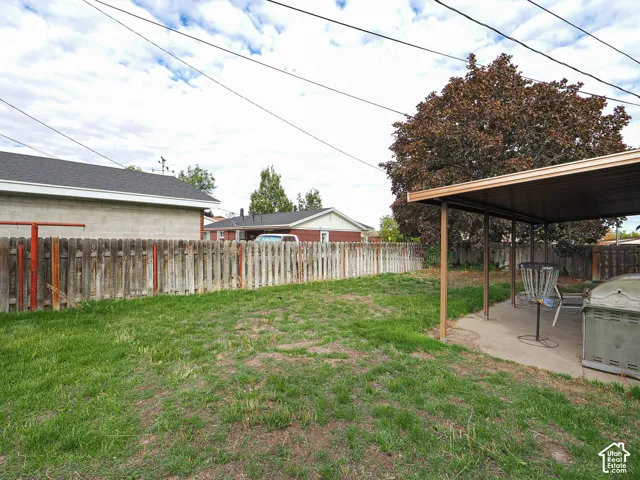 Backyard featuring a concrete patio, a covered structure, and a wood privacy fence