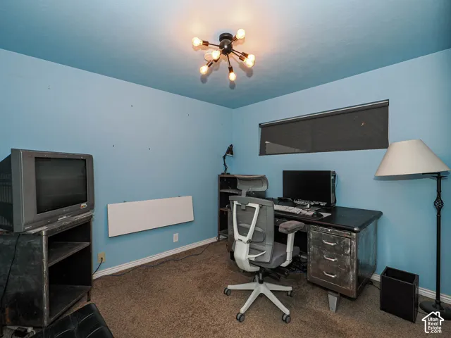 Spacious room featuring neutral carpeting, a horizontal window with a fitted roller shade, and a multi-arm sputnik-style ceiling light fixture