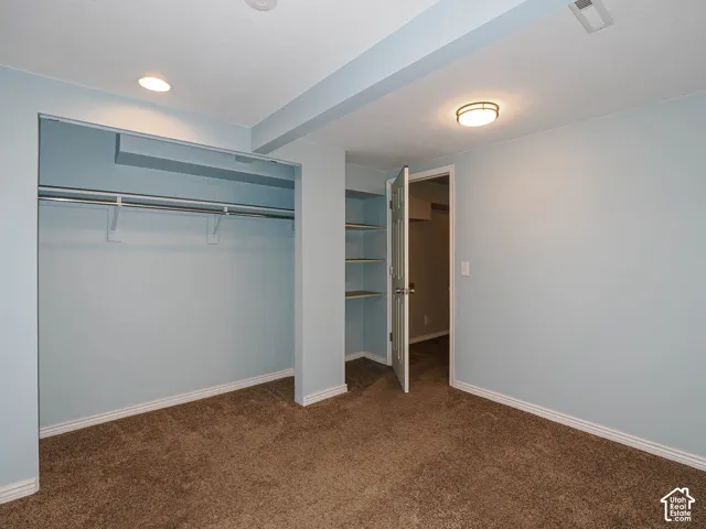 Room featuring neutral carpeting, recessed ceiling lighting, a built-in closet with overhead shelving, and integrated wall shelving
