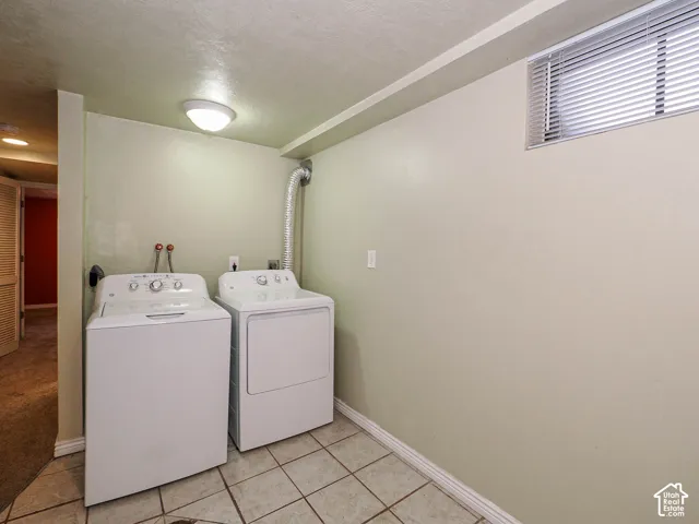 Laundry area featuring ceramic tile flooring, neutral wall paint, and a high-set window with integrated blinds