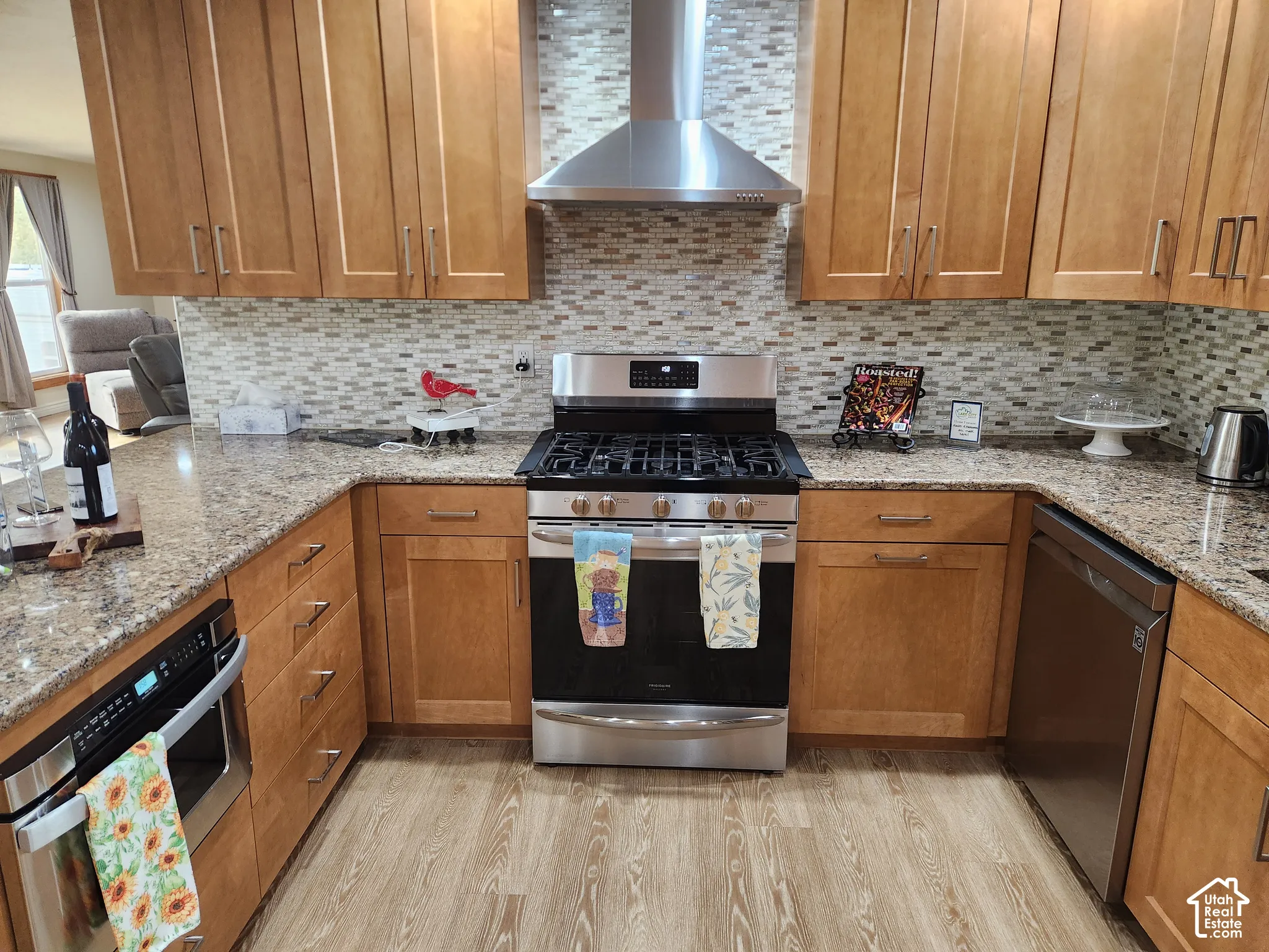 Kitchen featuring shaker-style cabinetry, stone-surface countertops, mosaic tile backsplash, stainless steel appliances, and wood-finish flooring