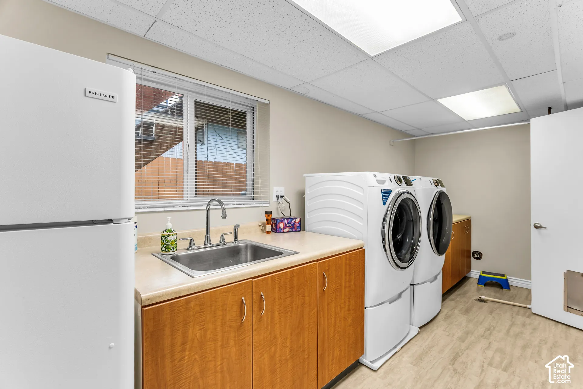 Utility room featuring wood-finish cabinetry, a stainless steel drop-in sink, integrated countertop, and recessed ceiling lighting
