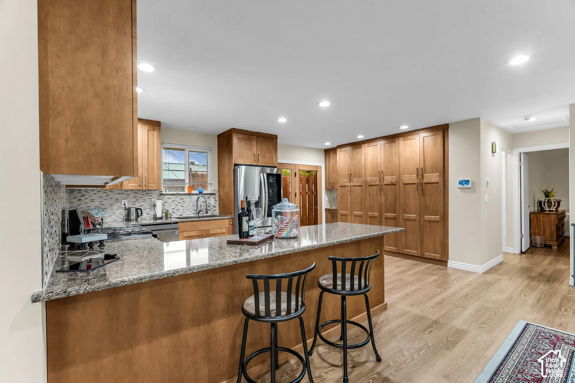 Kitchen featuring wood cabinetry, stone countertops, integrated cabinetry wall storage, recessed lighting, and wood-finish flooring