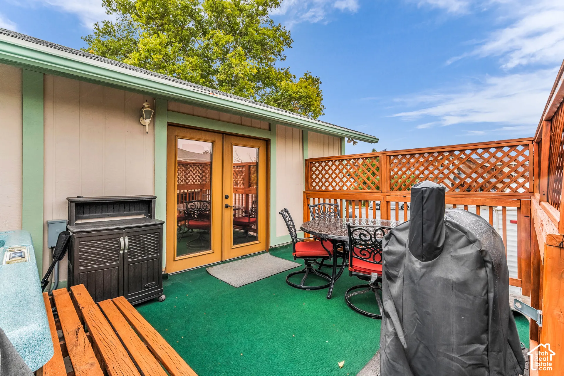 Outdoor patio featuring wood-frame latticework privacy fencing, dual-pane glass entry doors, and wall-mounted exterior lighting