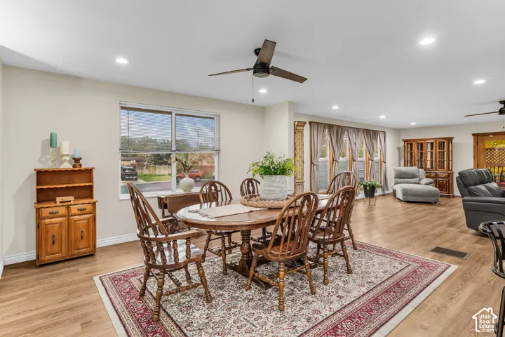 Open-concept space featuring wood-finish flooring, recessed lighting, ceiling fans, and large windows with natural light