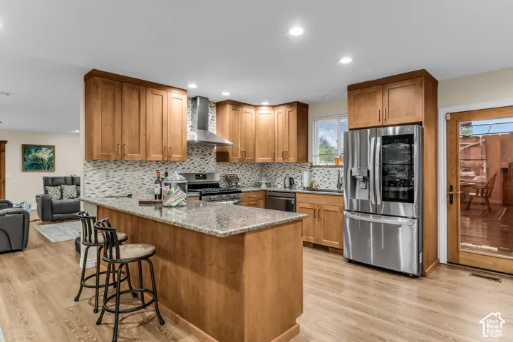 Kitchen featuring wooden cabinetry, stone-surface countertops, stainless steel appliances, a mosaic tile backsplash, and wood-finish flooring