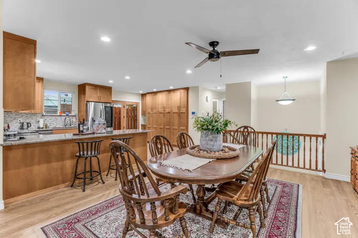 Open-concept interior featuring wood-finish flooring, recessed lighting, wood cabinetry, a stone-surfaced kitchen island, and a wooden stair railing