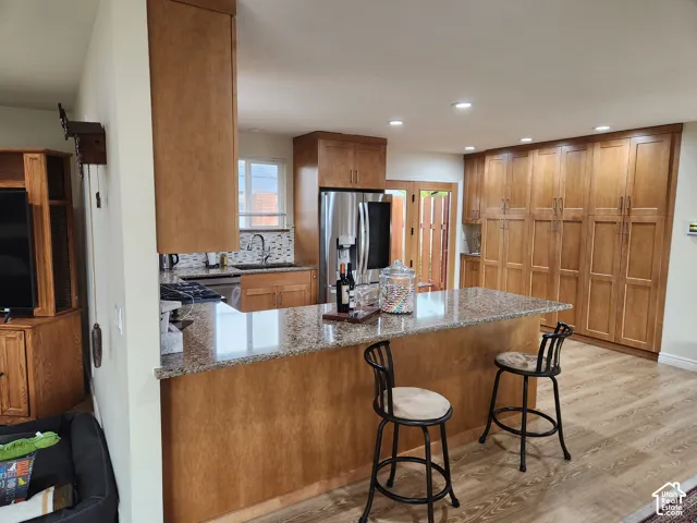Kitchen featuring shaker-style cabinetry, an expansive stone countertop island, recessed lighting, wood-finish flooring, and stainless steel appliances