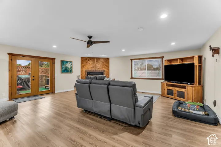 Living space featuring wood-finish flooring, recessed lighting, a ceiling fan, and a fireplace with a chevron-patterned wood surround