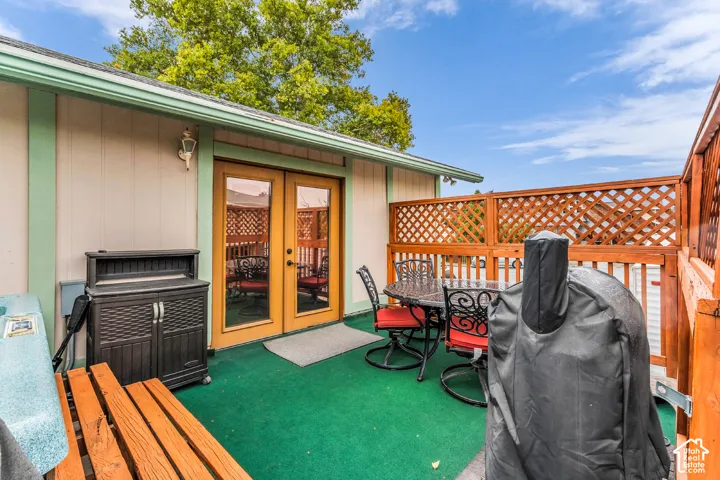 Outdoor patio featuring wood-frame latticework privacy fencing, dual-pane glass entry doors, and wall-mounted exterior lighting