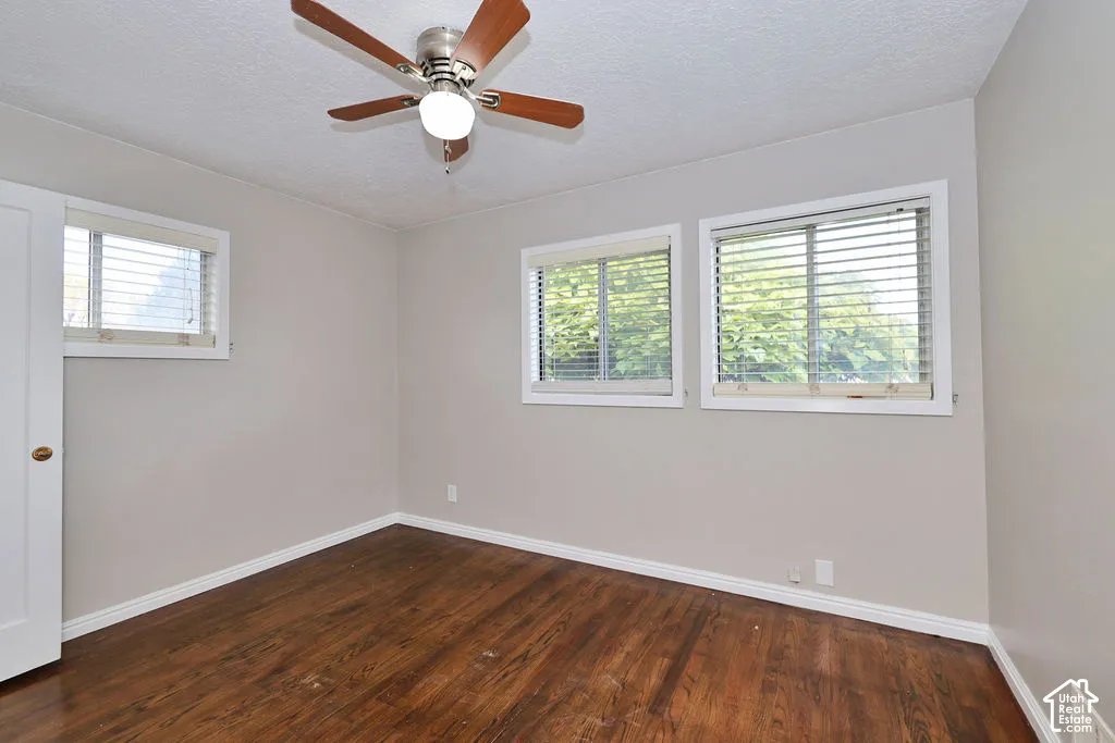 Room featuring wood-finish flooring, three double-pane windows with horizontal blinds, and a ceiling fan with integrated lighting