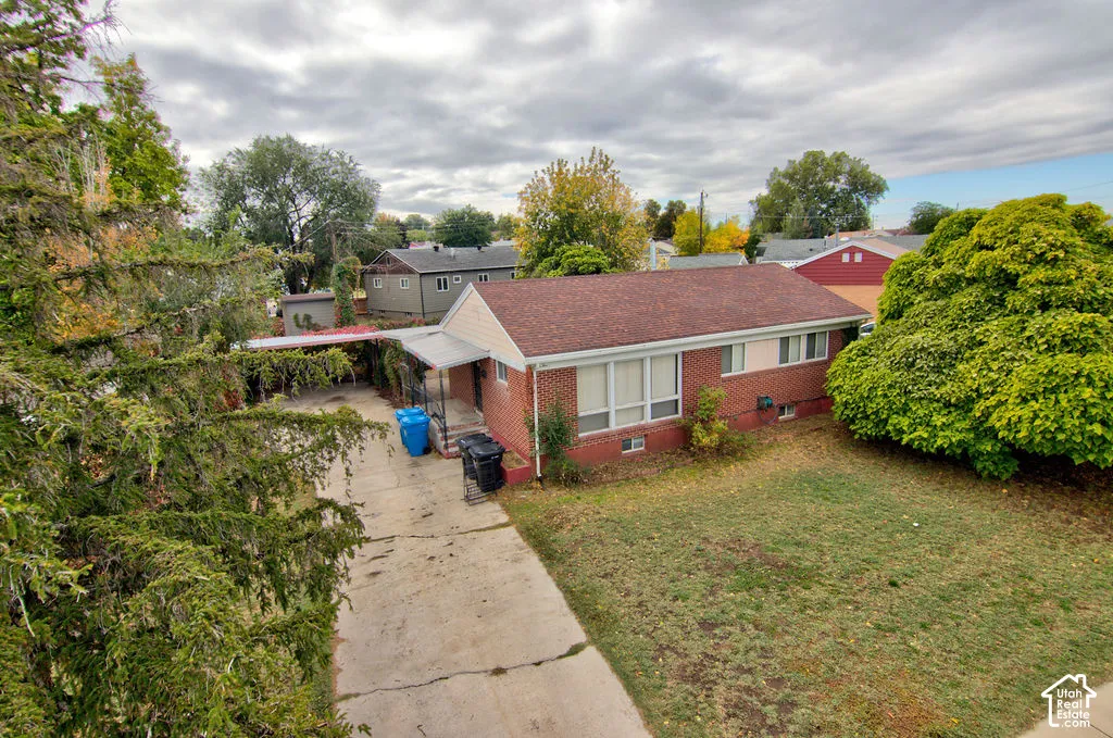 Single-story brick exterior residence featuring a composite shingle roof, concrete driveway, and attached carport