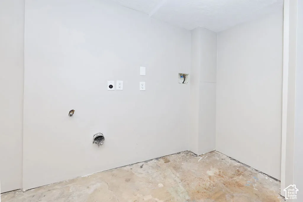 Utility area featuring unfinished concrete flooring, neutral-toned walls, and dedicated electrical and plumbing hookups