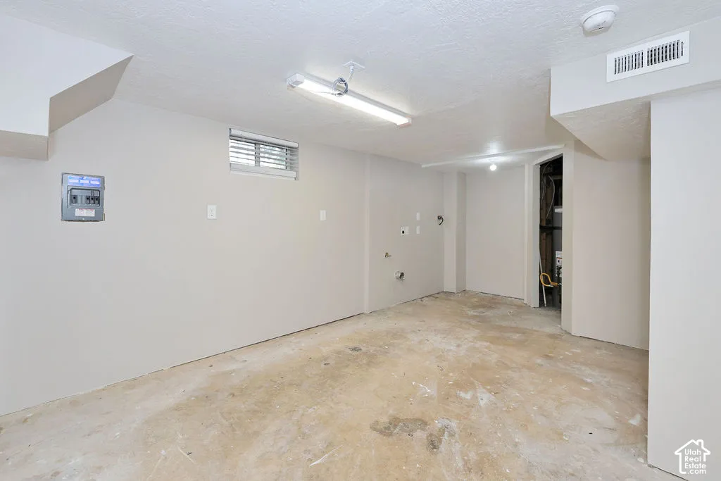 Neutral-toned interior space featuring overhead fluorescent lighting, an inset window, and a wall-mounted electrical panel