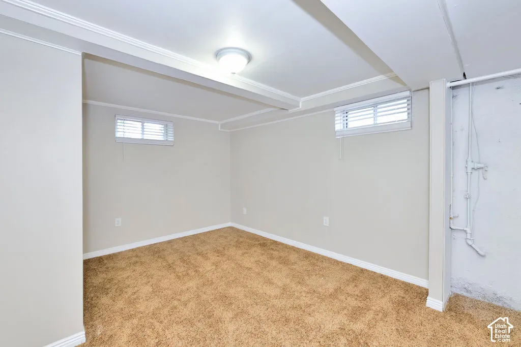 Carpeted interior featuring neutral-toned walls, structural ceiling beams, two rectangular windows with horizontal blinds, and a flush-mount ceiling fixture