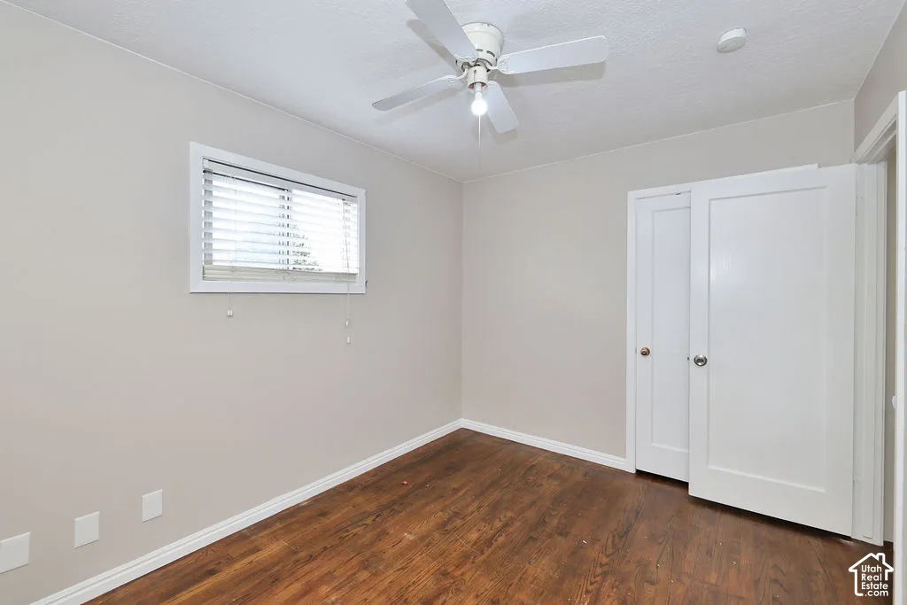 Interior space featuring wood-finish flooring, a ceiling fan, a window with horizontal blinds, and paneled doors