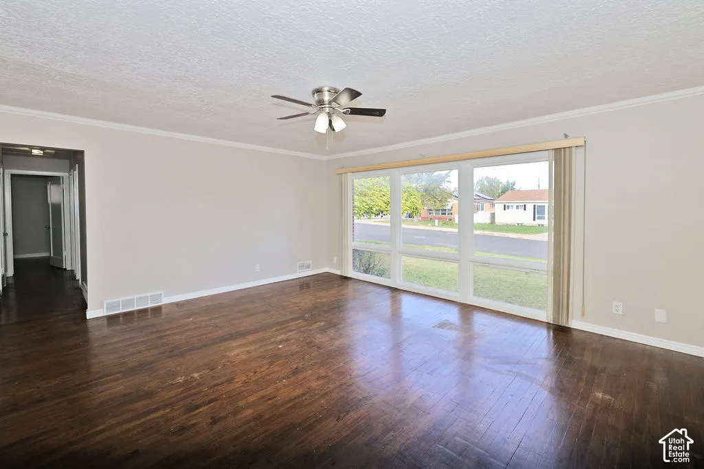 Large windows, wood-finish flooring, and a ceiling-mounted light fixture with fan