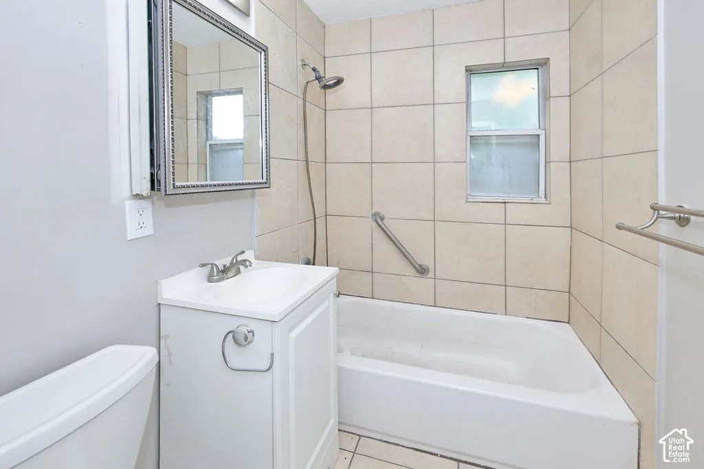 Bathroom featuring a white vanity cabinet, square wall tile surround, tub and shower combination, integrated metal safety bar, and a rectangular mirror with a decorative frame
