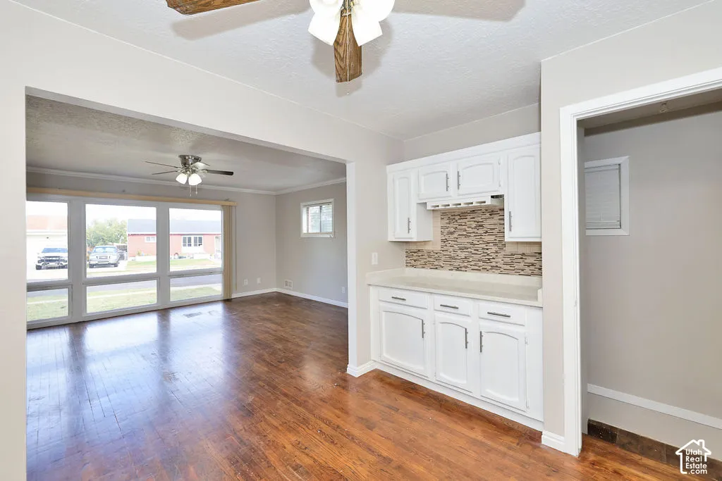 Interior featuring wood-finish flooring, white cabinetry, and a textured tile backsplash