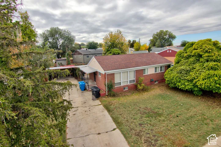 Single-story brick exterior residence featuring a composite shingle roof, concrete driveway, and attached carport