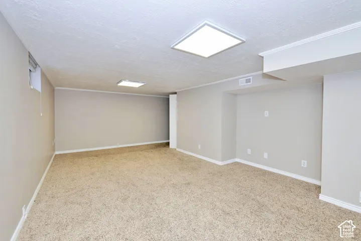 Neutral-toned interior space featuring neutral carpeting, recessed square LED lighting fixtures, and inset wall niches