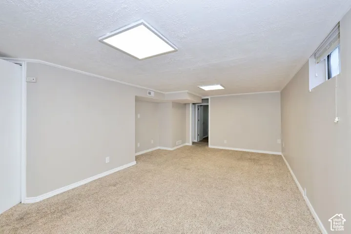Open interior space featuring neutral wall tones, wall-to-wall carpeting, and recessed square LED lighting fixtures