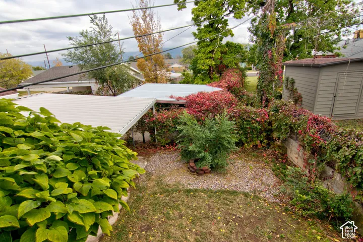 Outdoor space featuring a gravel ground cover, metal carport, detached storage structure, and stone retaining wall