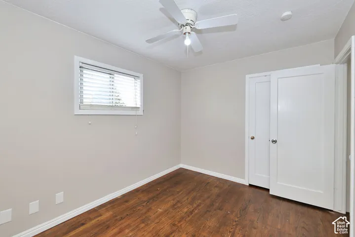 Interior space featuring wood-finish flooring, a ceiling fan, a window with horizontal blinds, and paneled doors
