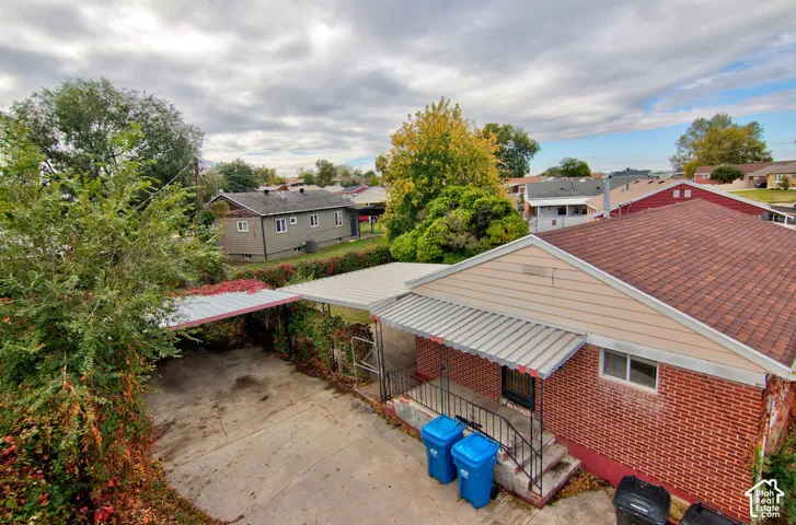 Exterior featuring red brick masonry, siding, shingled roofing, a concrete driveway, and a covered carport