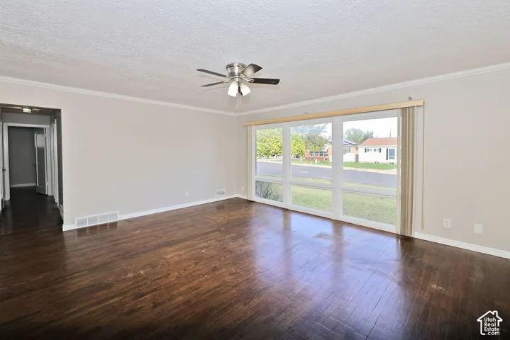 Large windows, wood-finish flooring, and a ceiling-mounted light fixture with fan