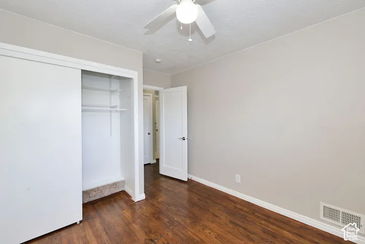 Room featuring wood-finish flooring, a ceiling fan with integrated lighting, and a reach-in closet with built-in wire shelving