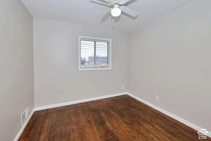 Interior space featuring wood-finish flooring, white trim, a single-pane window, and a ceiling-mounted light fixture with a white fan