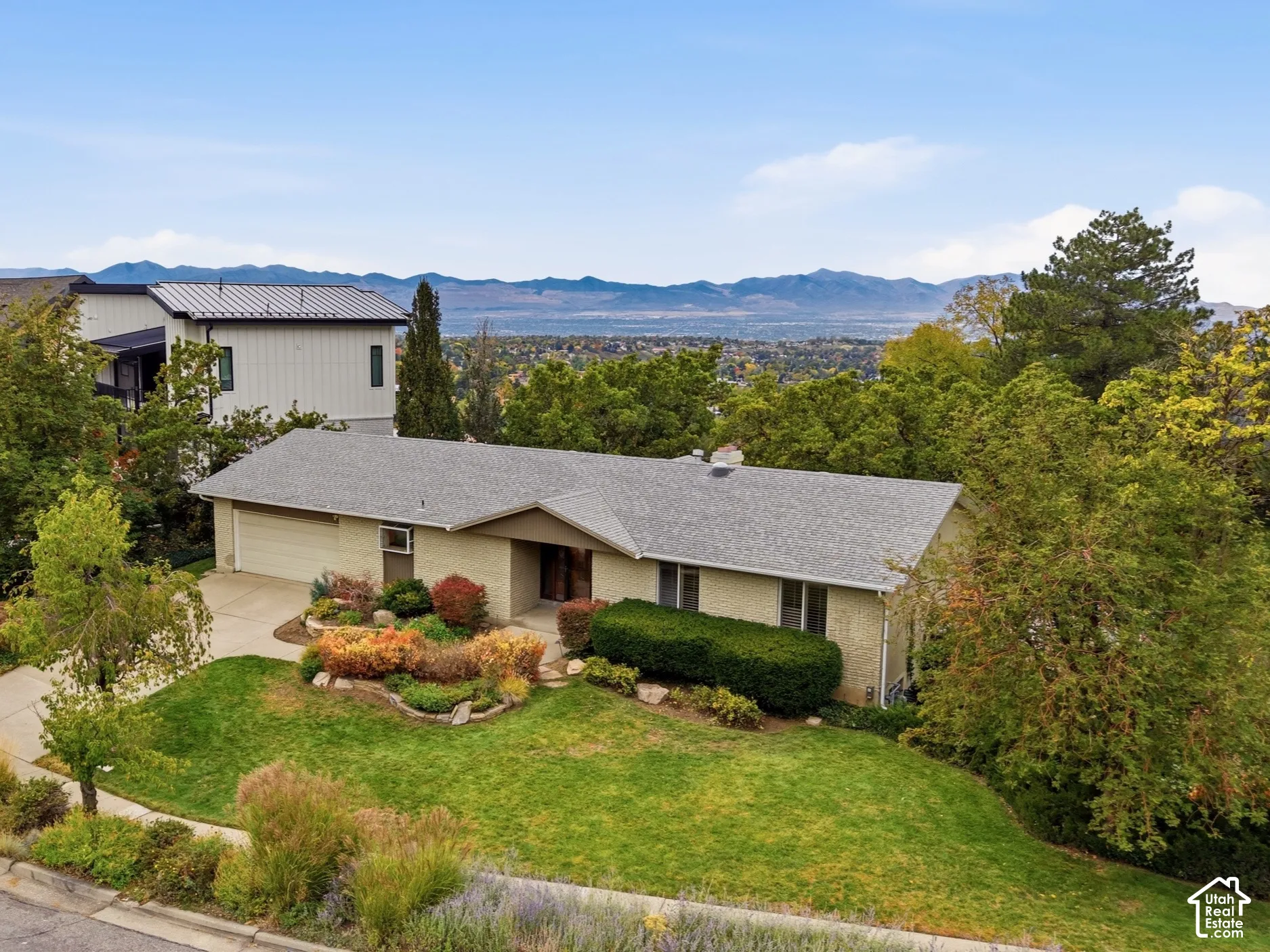 Single-level residence with a multi-car garage, manicured lawn, established landscaping, and mountain backdrop.
