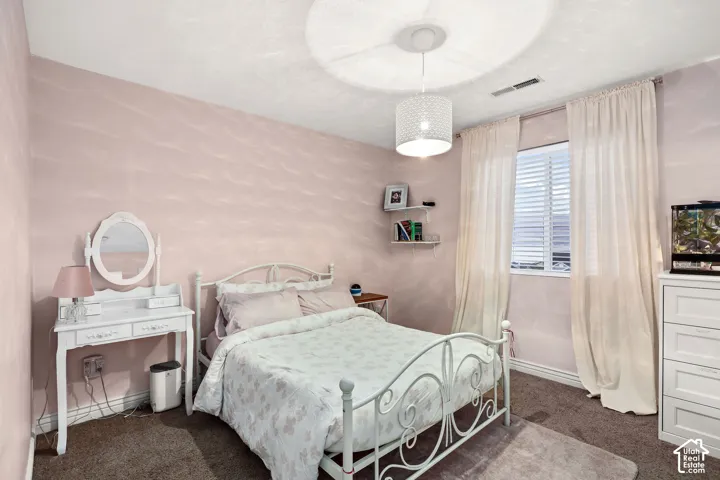Textured wall finishes, carpeted flooring, window with installed horizontal blinds, and a drum-style pendant light fixture