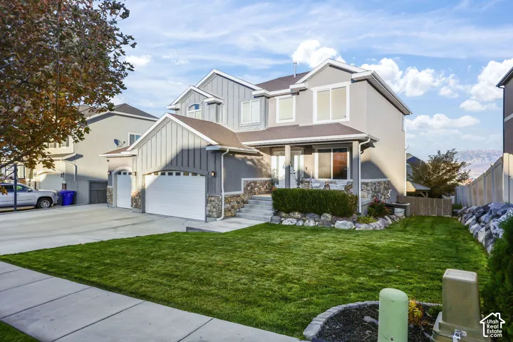Two-story residence featuring vertical and horizontal siding, a stone veneer foundation, an attached three-car garage, and a concrete driveway