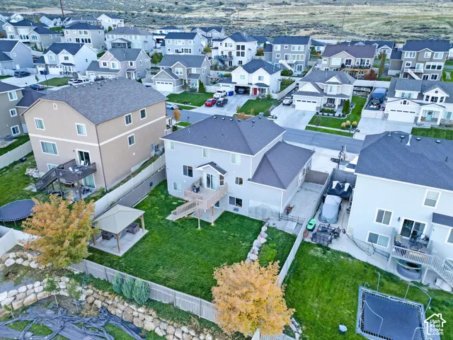 Aerial perspective of a multi-story residence featuring a raised wood deck, a fenced rear yard, and a stone retaining wall