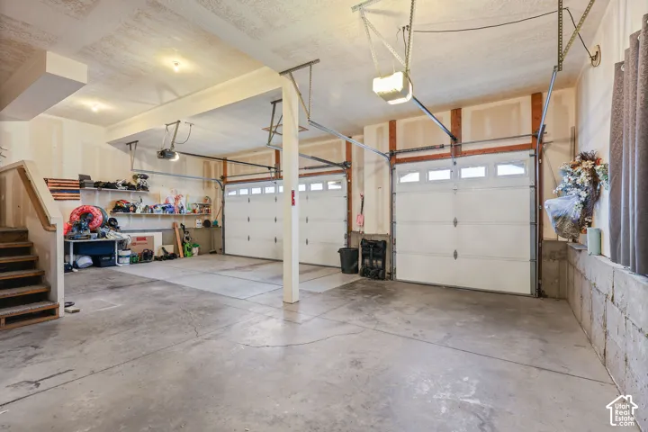 Three-car garage featuring concrete flooring, three overhead paneled doors with windows, two automated openers, and built-in wall shelving